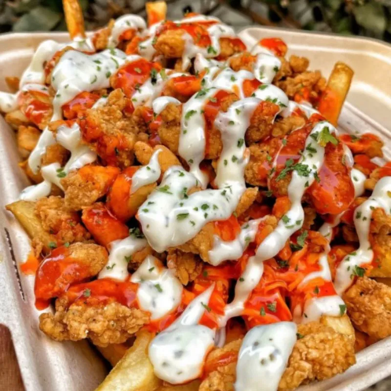 Loaded fries topped with fried chicken chunks and two creamy sauces at Wild Crab House, a Seafood Restaurant in Staten Island